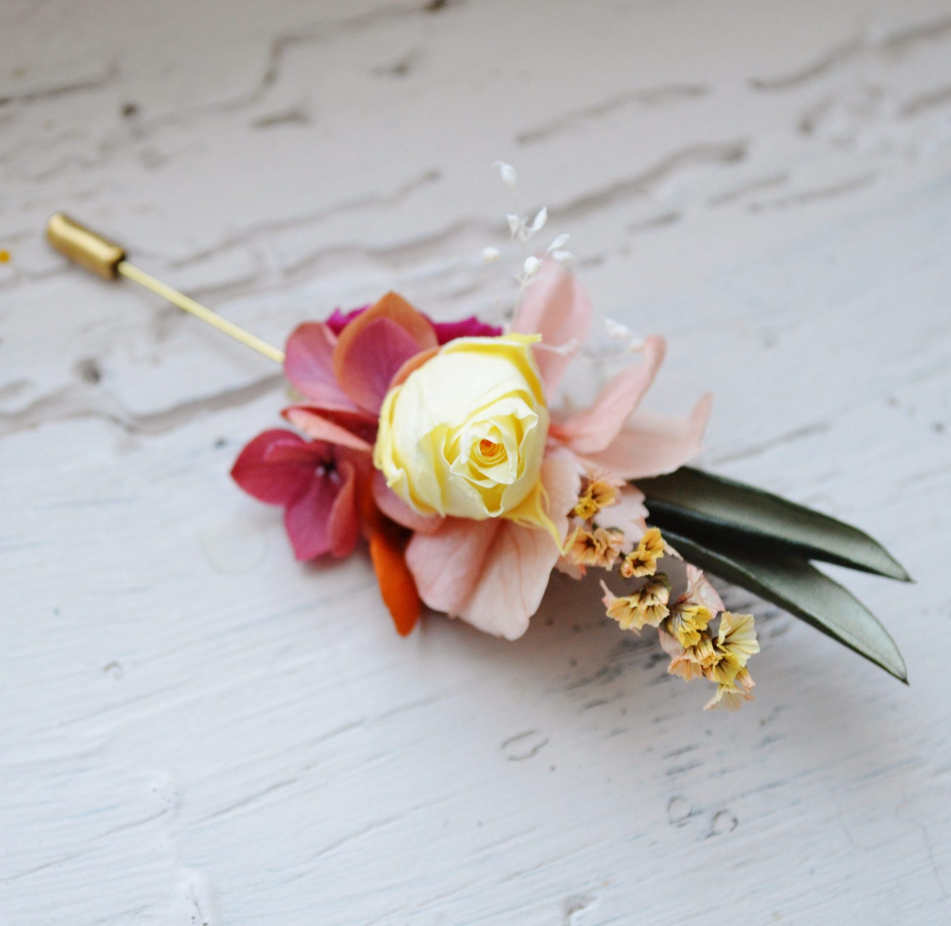 Boutonniere mariage fleurs stabilisees colorees fuchsia orange et feuilles d olivier bijoux mariage collection flamenco